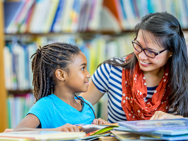 woman reading with school age girl